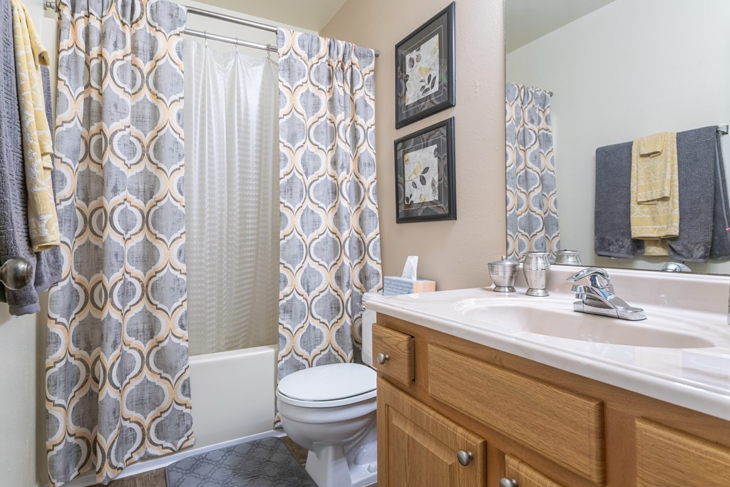 A bathroom with a toilet, sink, and shower curtain Fishermans Landing Apartments in Ormond Beach, FL.
