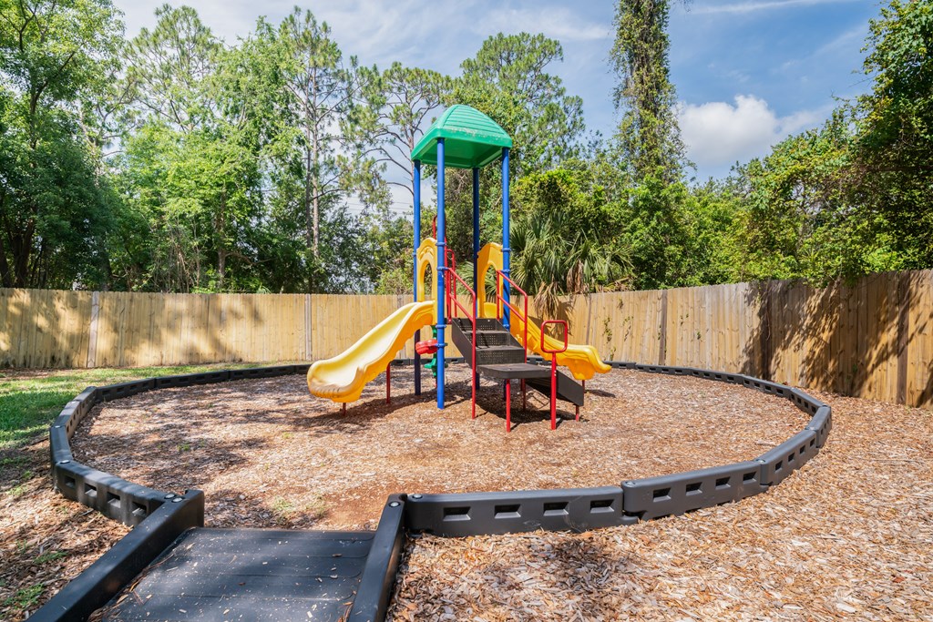 A playground with a yellow slide and a green roof Fishermans Landing Apartments in Ormond Beach, FL.