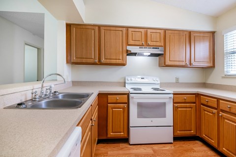 A kitchen with wooden cabinets and a white stove top oven.