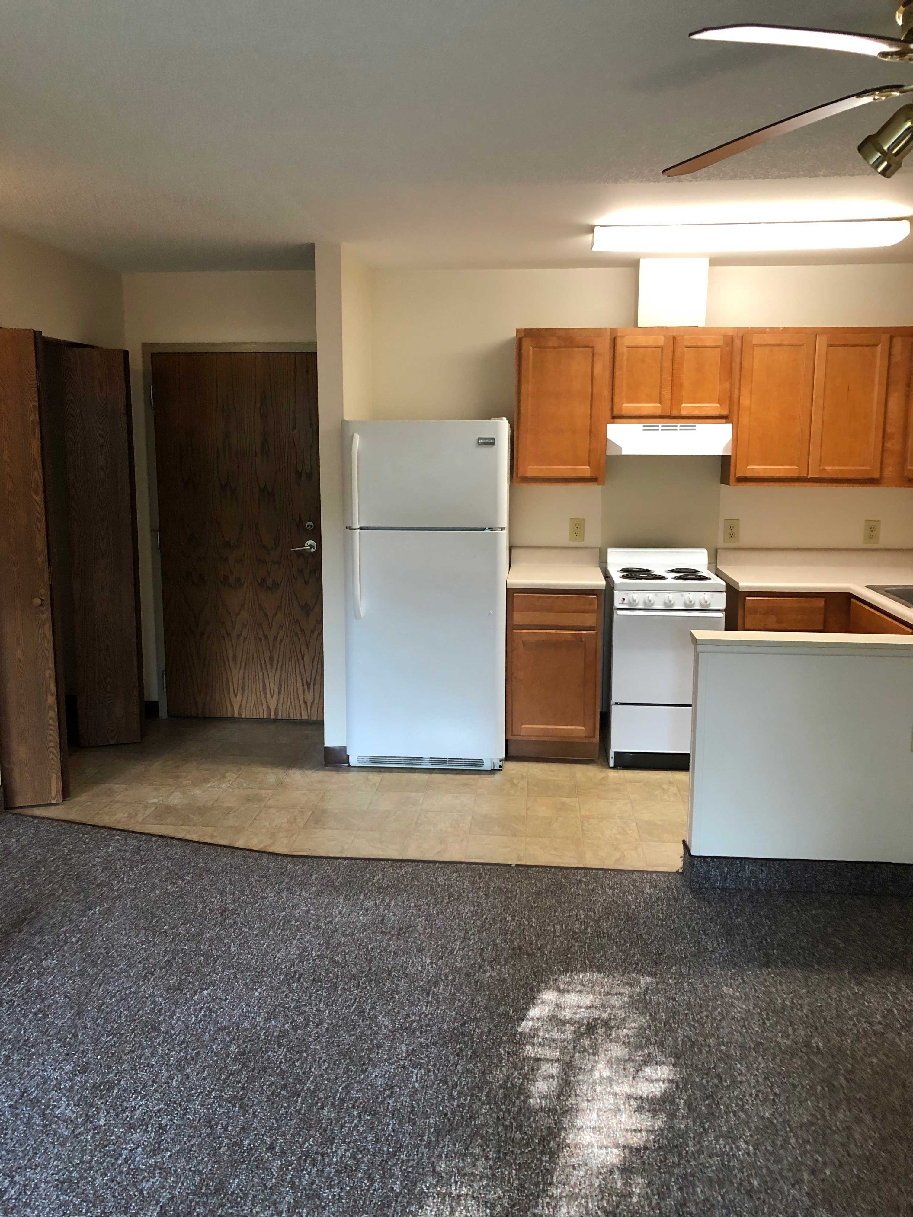 A kitchen with a white refrigerator and wooden cabinets.