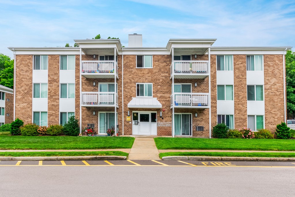 an apartment building with a sidewalk and grassat North Stoughton Village, Stoughton, Massachusetts