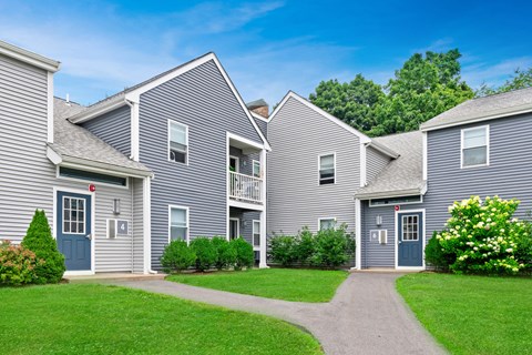 a row of houses with blue siding and green grass at Blue Hills Village, Canton, Massachusetts