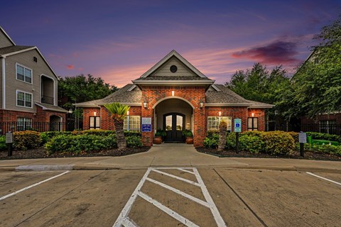 A building with a brick facade and a triangular roof is surrounded by a parking lot.