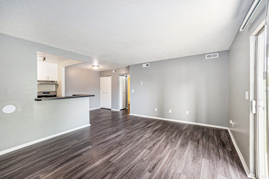 a spacious living room with a kitchen in the background