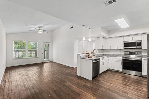 A spacious kitchen with white cabinets and a wooden floor.