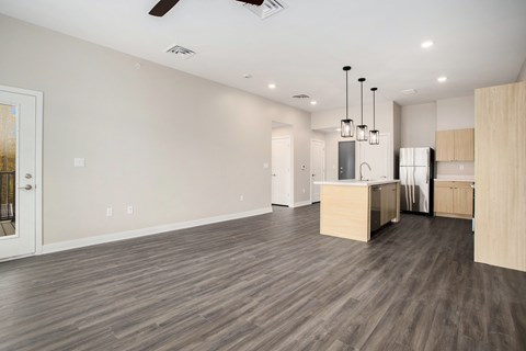 A spacious kitchen with wooden floors and a ceiling fan.