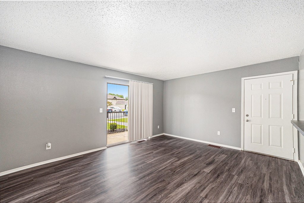an empty living room with a door leading to a balcony