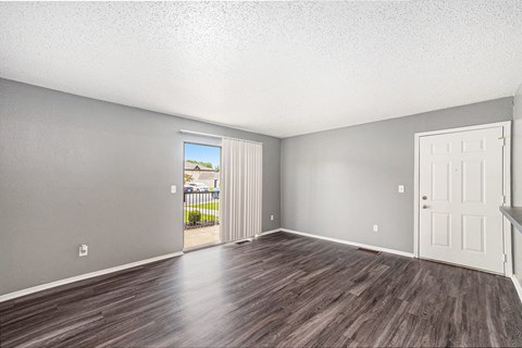 an empty living room with a door leading to a balcony