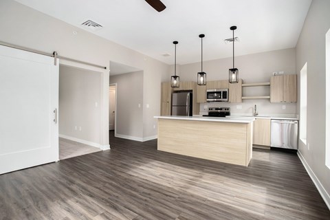 A kitchen with a wooden floor and a white ceiling fan.
