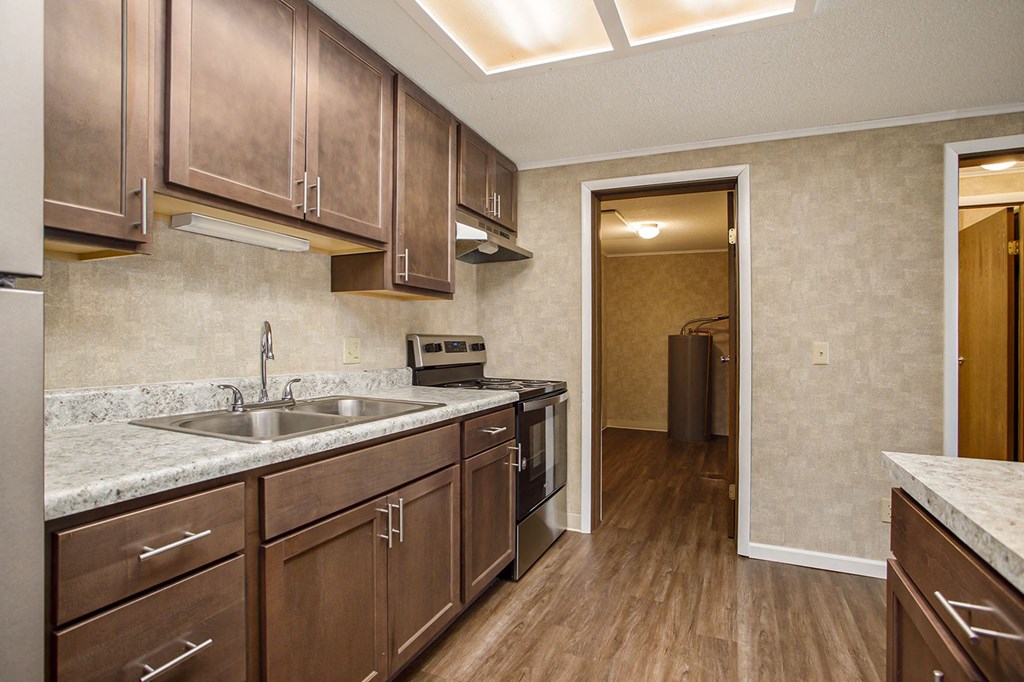 a kitchen with dark wood cabinets and a stainless steel sink