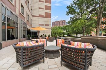 Two wicker chairs with colorful cushions are placed on a patio.