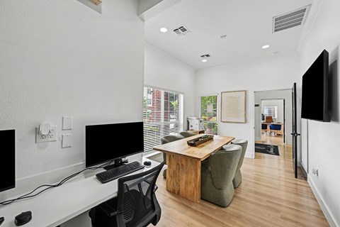 A modern home office with a desk, chairs, and computer monitors.
