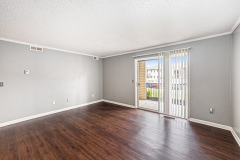 a living room with hardwood floors and a glass door leading to a balcony