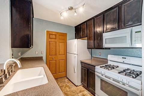 a kitchen with a white refrigerator freezer next to a white stove top oven