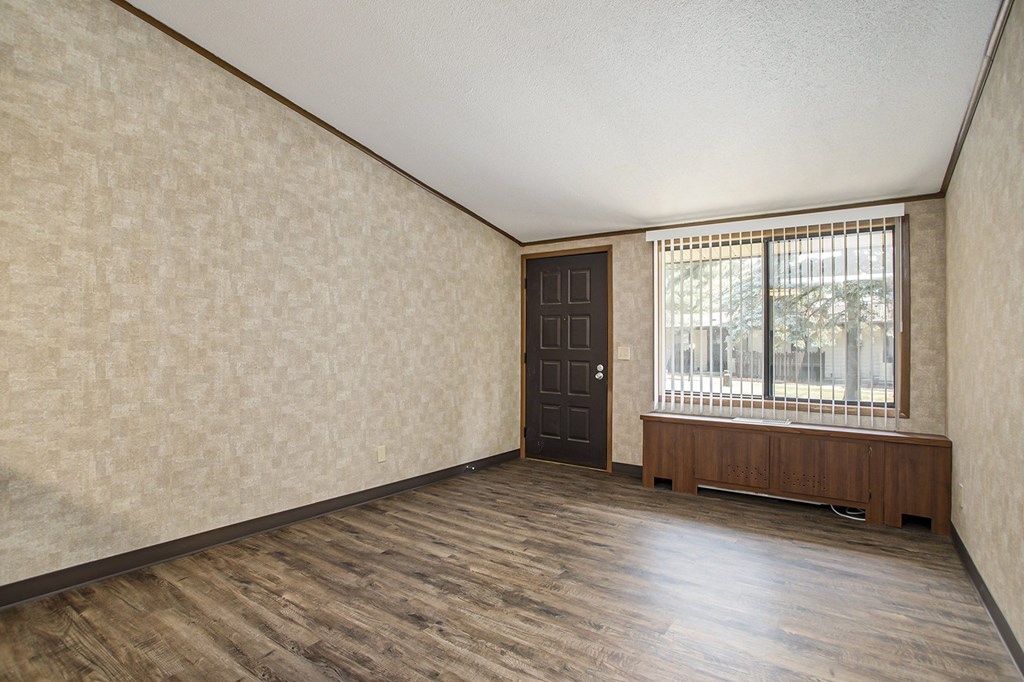 an empty living room with a large window and wooden floors