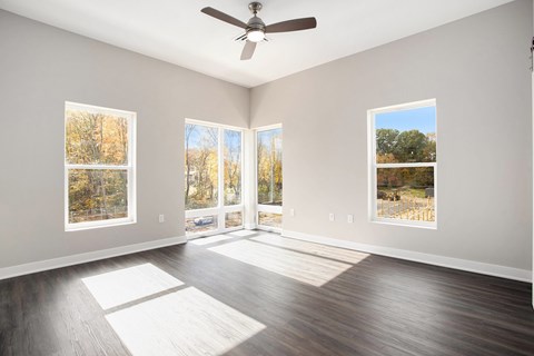 A room with a ceiling fan and sliding glass doors.