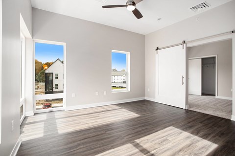 A spacious room with a ceiling fan and two windows.