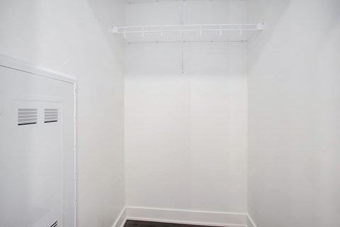 A white closet with a door and a shelf above it.