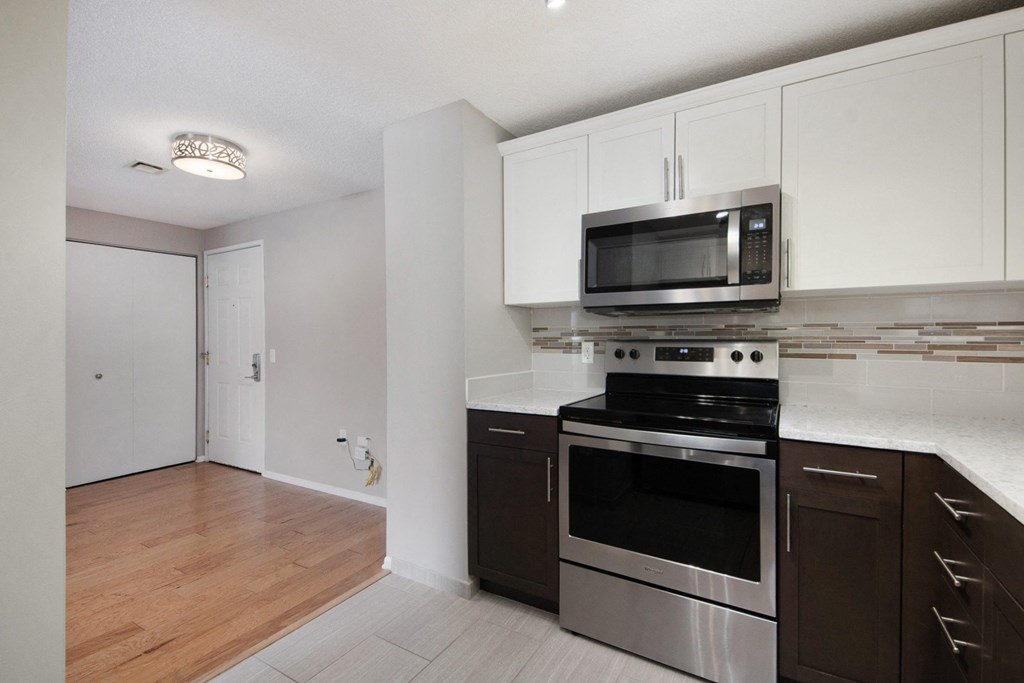 an empty kitchen with stainless steel appliances and white cabinets