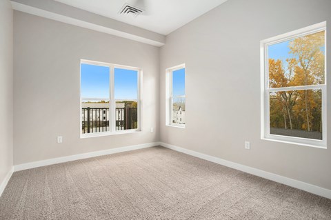 A room with two windows, one of which shows a view of trees.