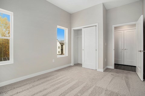 A room with a carpeted floor and a window showing trees outside.