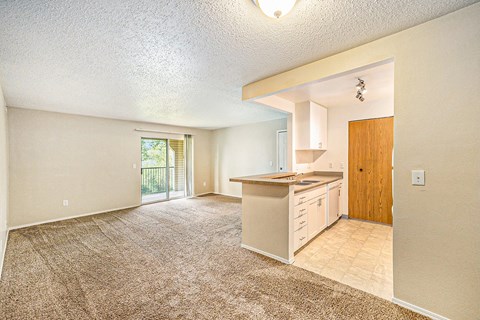 a kitchen and living room with a door to a balcony