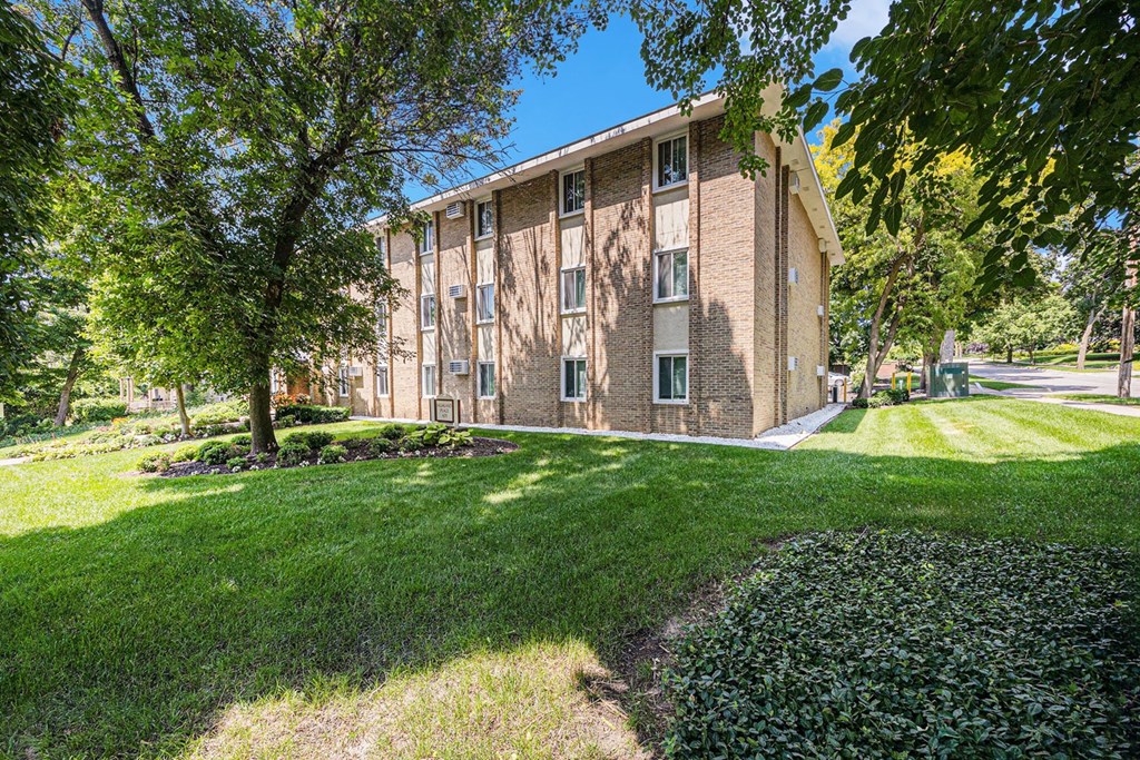 a brick building with trees and grass in front of it