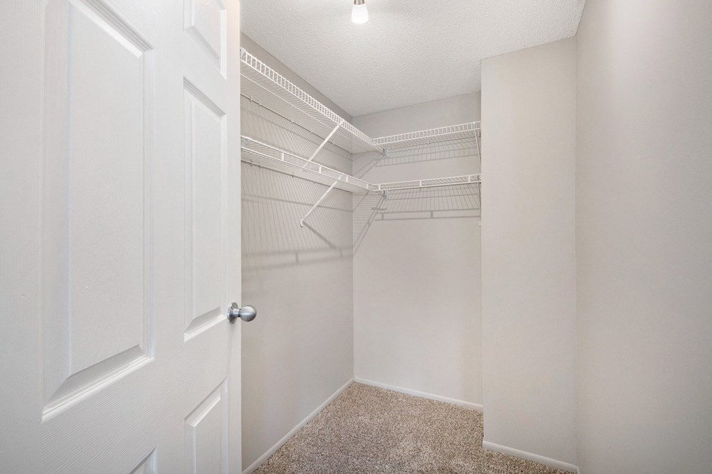 an empty closet with white walls and a white door