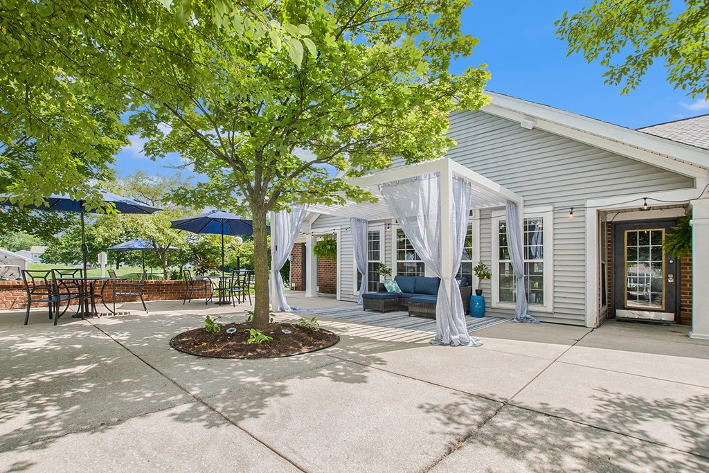 a patio with a tree and a white house