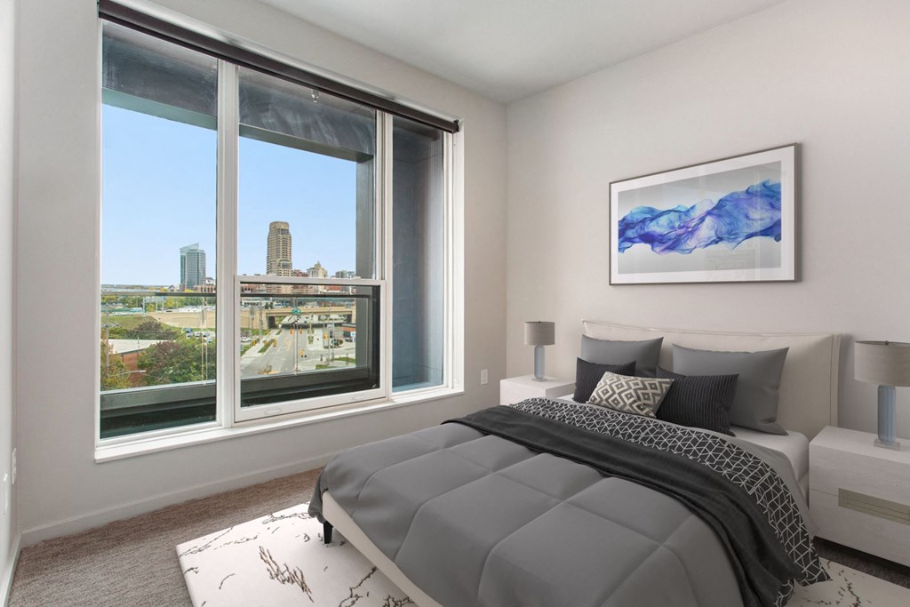 a bedroom with a bed and a large window with a city view