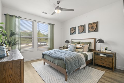 A bedroom with a bed, nightstand, and a ceiling fan.