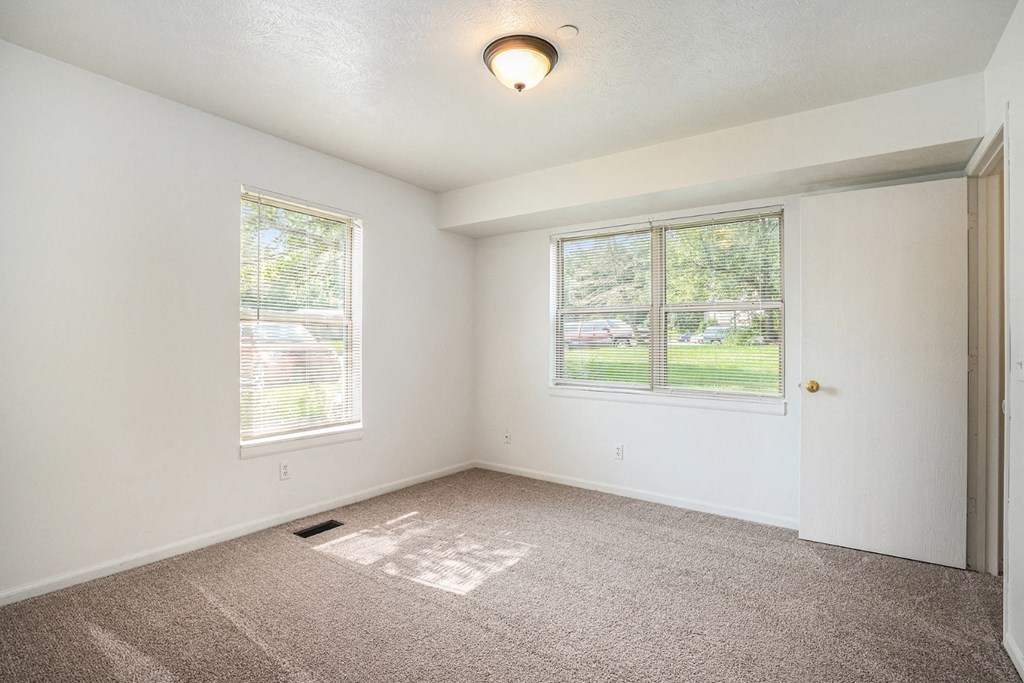 a bedroom with two windows and a door