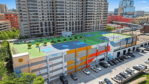 A tennis court is located on the roof of a parking garage.