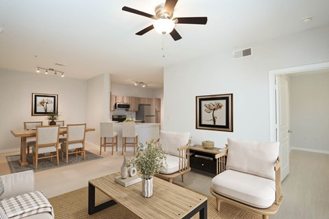 A living room with a ceiling fan and a dining table with chairs.