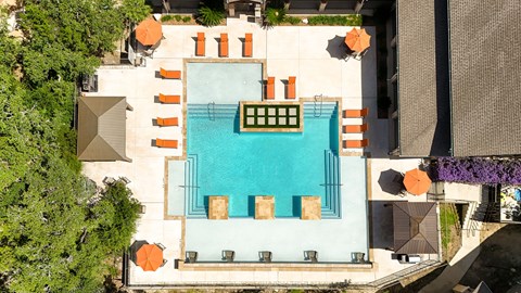 An aerial view of a pool surrounded by orange chairs and green plants.