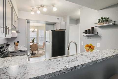 a kitchen with granite counter tops and a stainless steel refrigerator