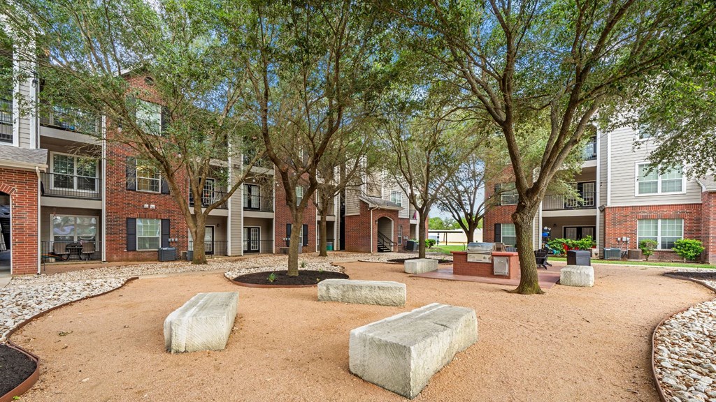 A courtyard with a sandy ground and a few trees.
