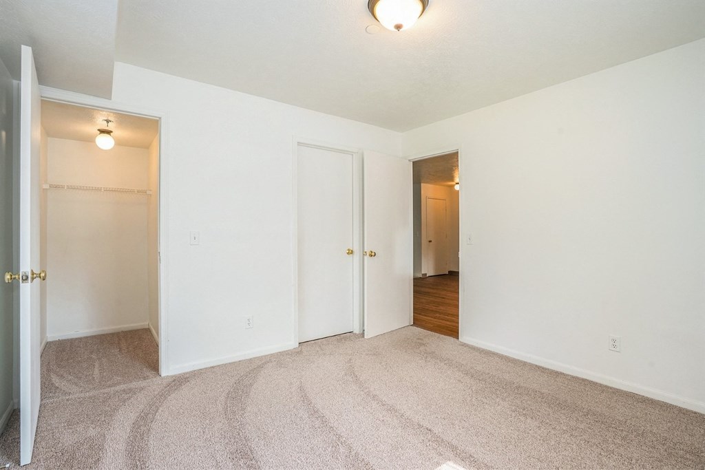 a bedroom with white walls and carpet