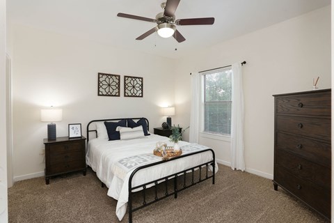 A bedroom with a bed, dresser, and ceiling fan.