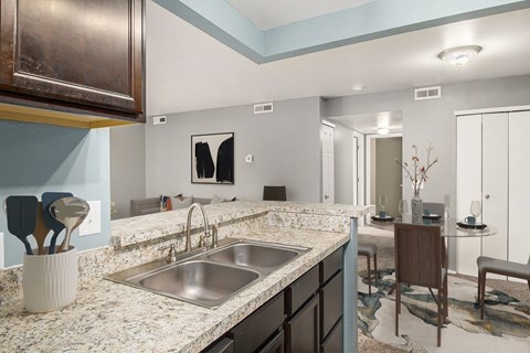 a kitchen with a sink and a counter top and a dining room
