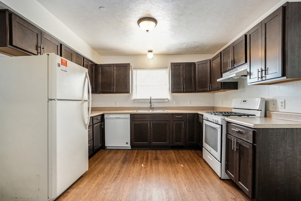 a kitchen with dark wood cabinets and white appliances