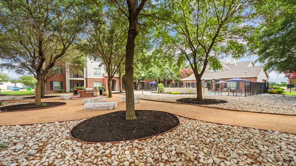 A tree in a circle of dirt is in the middle of a circle of gravel.
