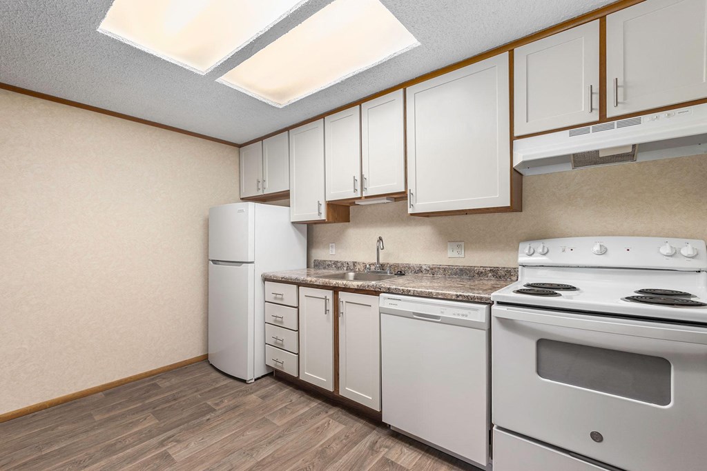 A kitchen with white appliances and wooden cabinets.