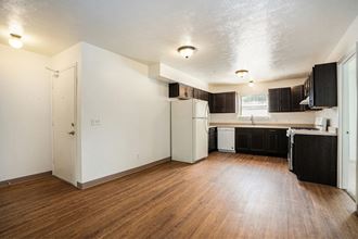 an empty kitchen and living room with hardwood floors and white walls