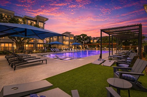 A beautiful outdoor swimming pool area with lounge chairs and a pergola.
