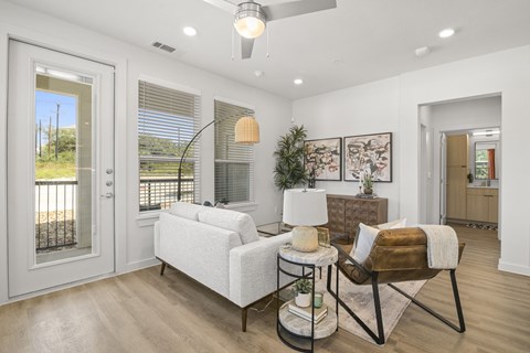 A living room with a white sofa and a chair with a brown cushion.