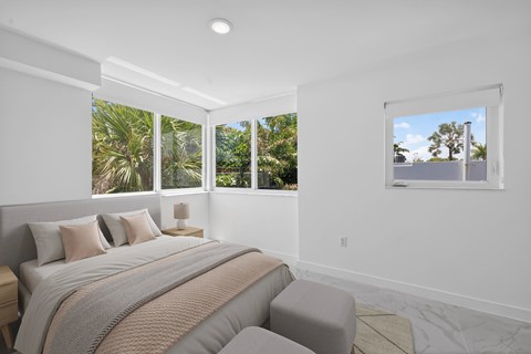 A bedroom with a large bed and a view of the outdoors through the windows.