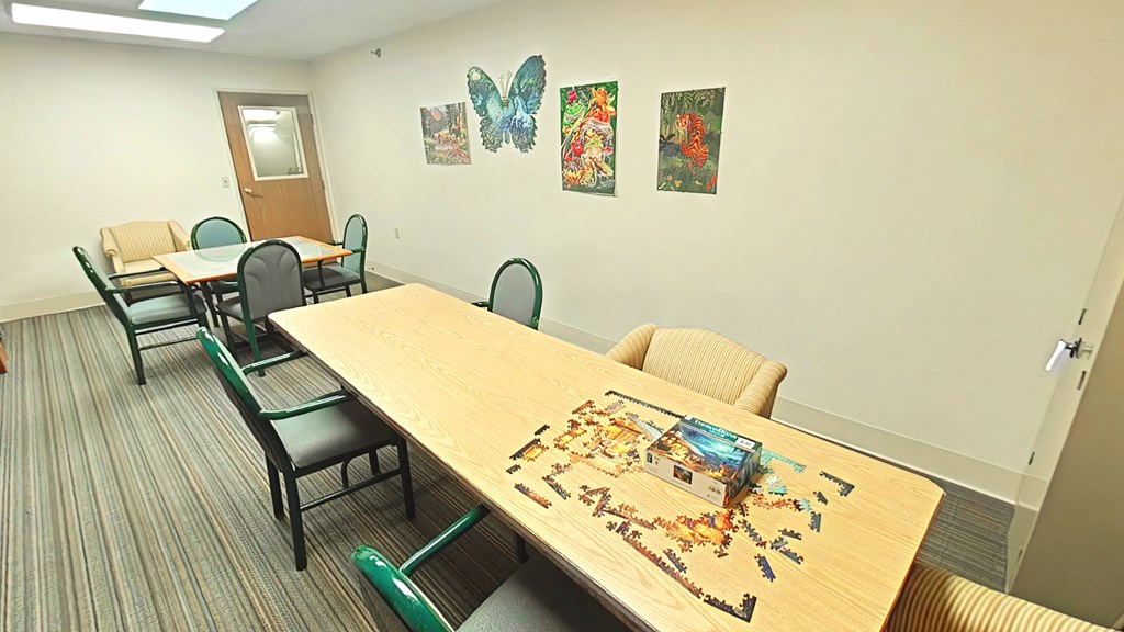 A conference room with a table surrounded by chairs and a box of Legos on the table.