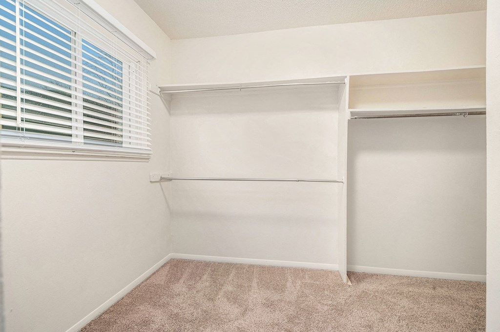 a bedroom with white walls and a window with white blinds