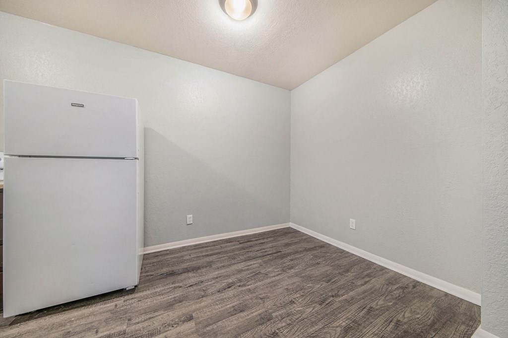 a bedroom with a refrigerator and hardwood floors